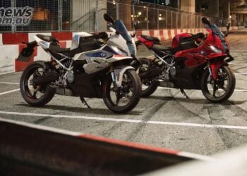 White and red BMW F 450 RR motorcycles parked beside red and white barriers at night