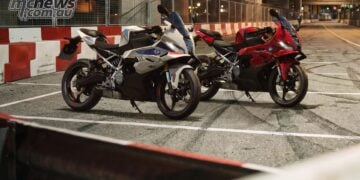 White and red BMW F 450 RR motorcycles parked beside red and white barriers at night