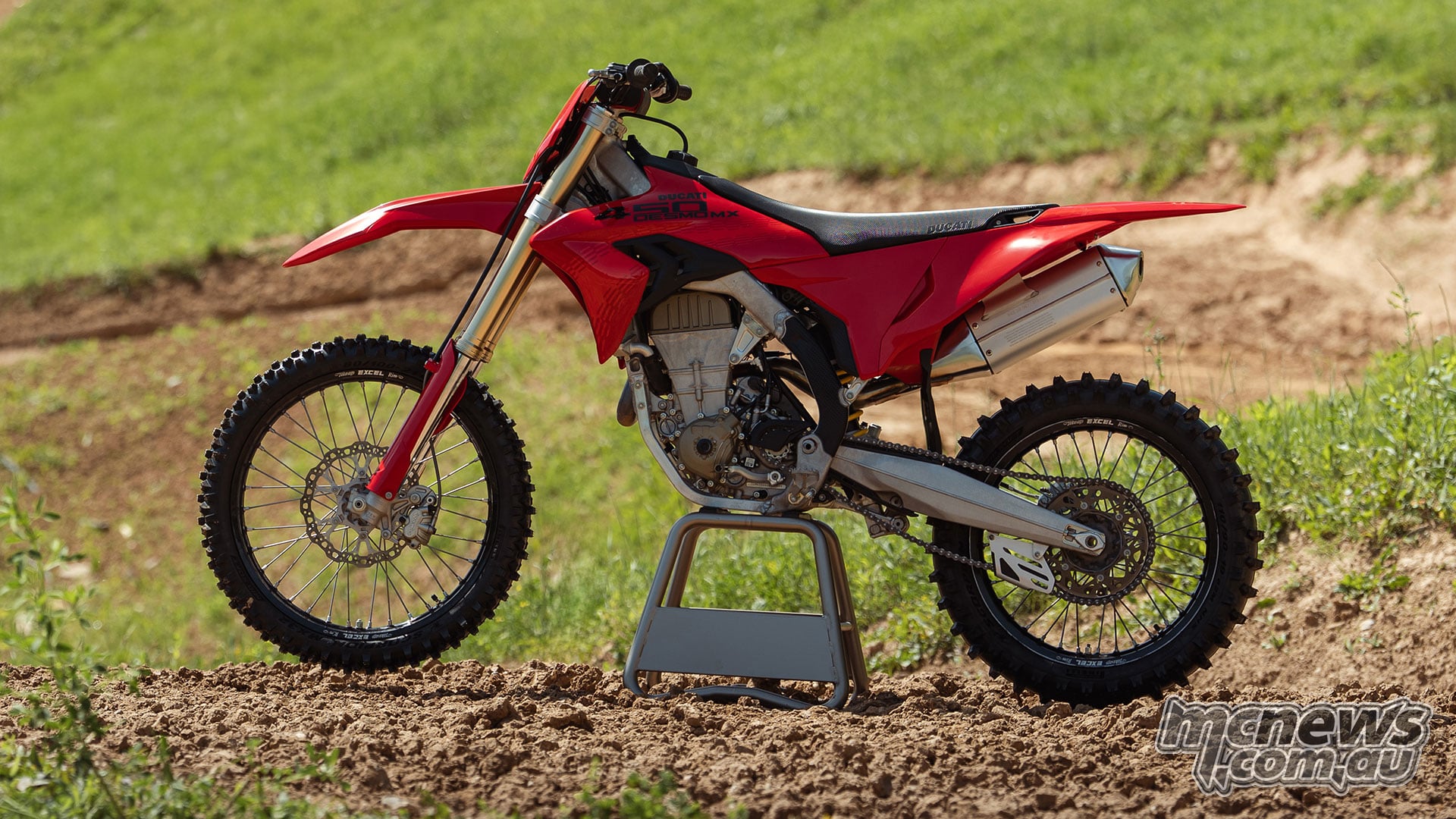 Complete side profile of the red 2027 Ducati Desmo450 MX showing its single-cylinder engine, aluminium frame, Showa forks, silver exhaust and motocross wheels.