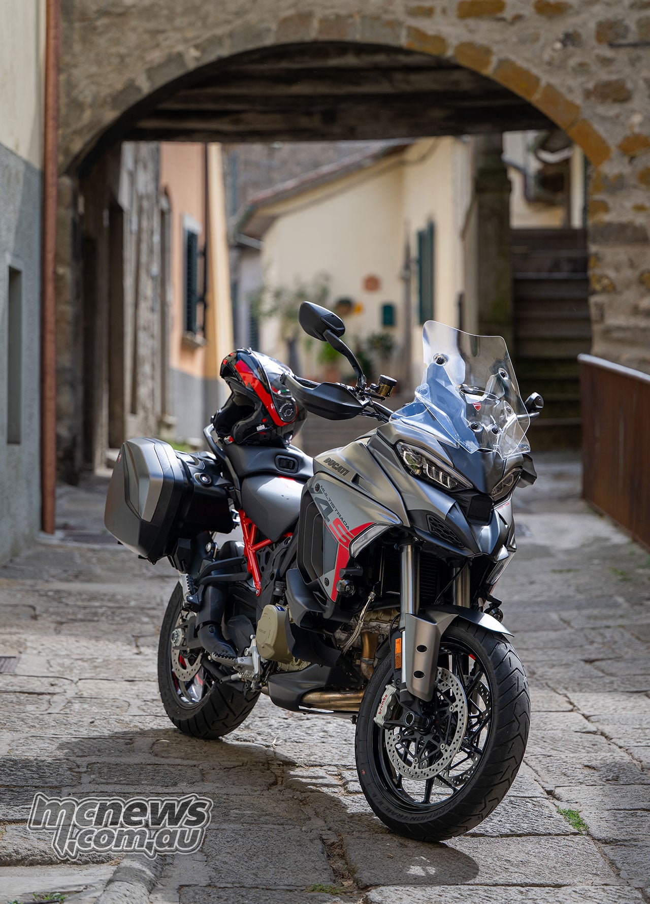 2027 Ducati Multistrada V4 S Grand Tour parked in an Italian laneway showing front Brembo brakes and alloy wheel