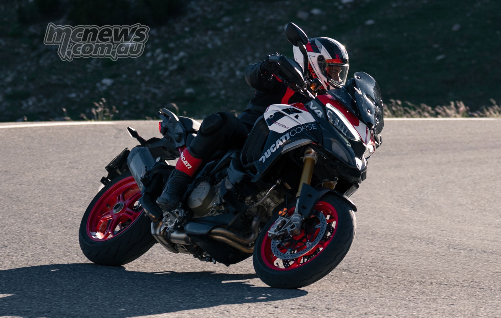 2027 Ducati Multistrada V4 Pikes Peak cornering on a mountain road with optional red forged wheels