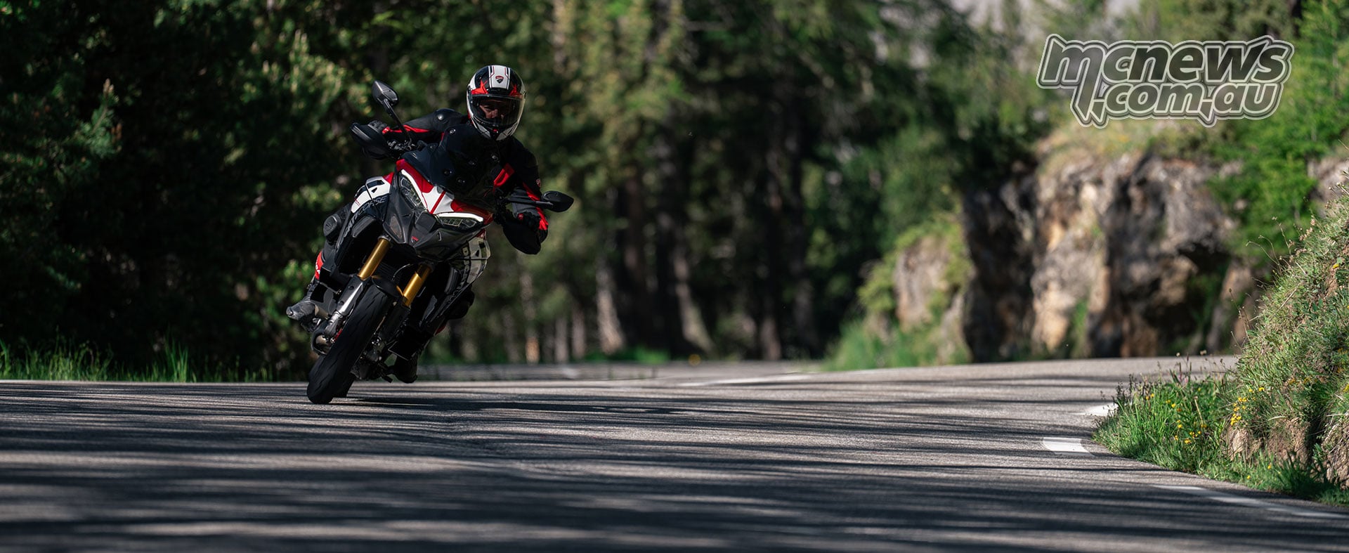 2027 Ducati Multistrada V4 Pikes Peak cornering through a tree-lined mountain road