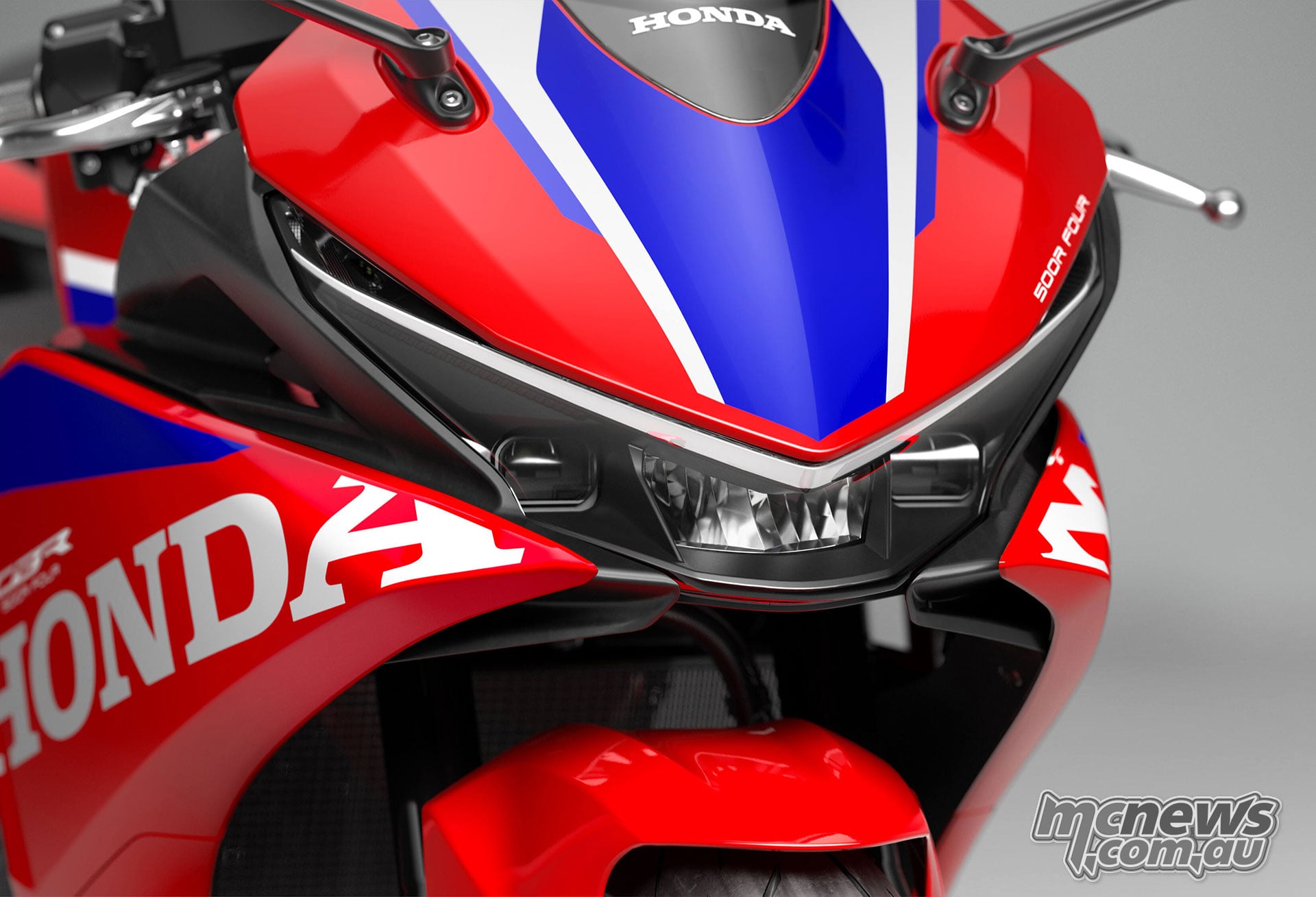 Close-up of the red, blue and white 2027 Honda CBR500R FOUR front fairing and headlight assembly