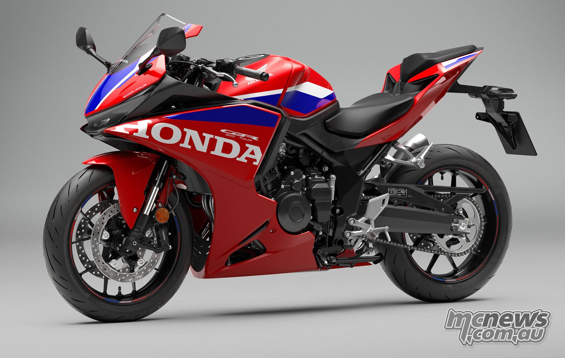 Full front left three-quarter studio view of the 2027 Honda CBR500R FOUR in Ignition Red tricolour