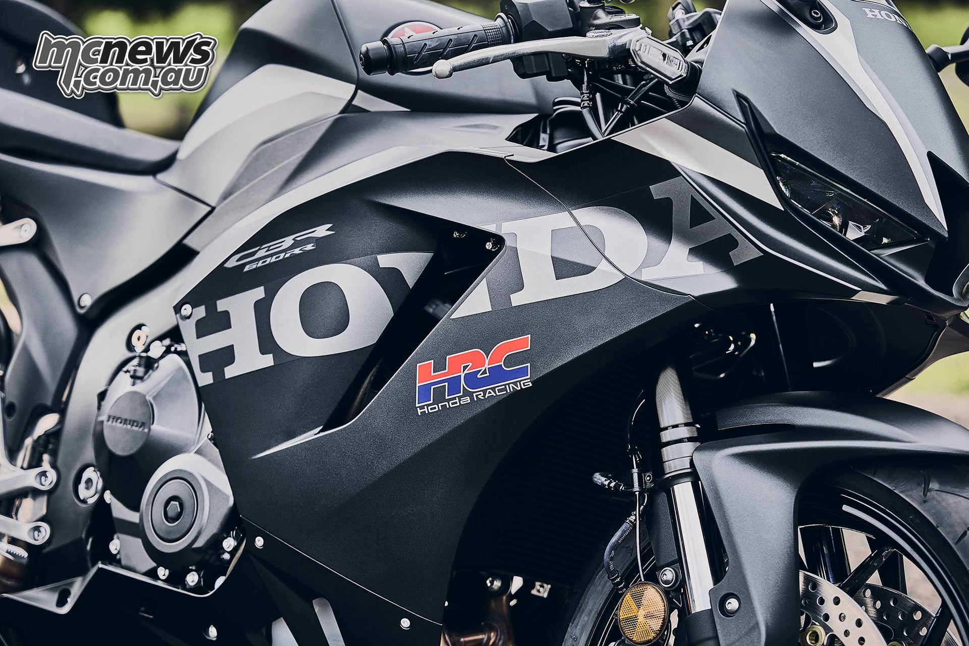 Close-up of the black 2027 Honda CBR600RR right fairing, grey Honda lettering and red and blue HRC logo