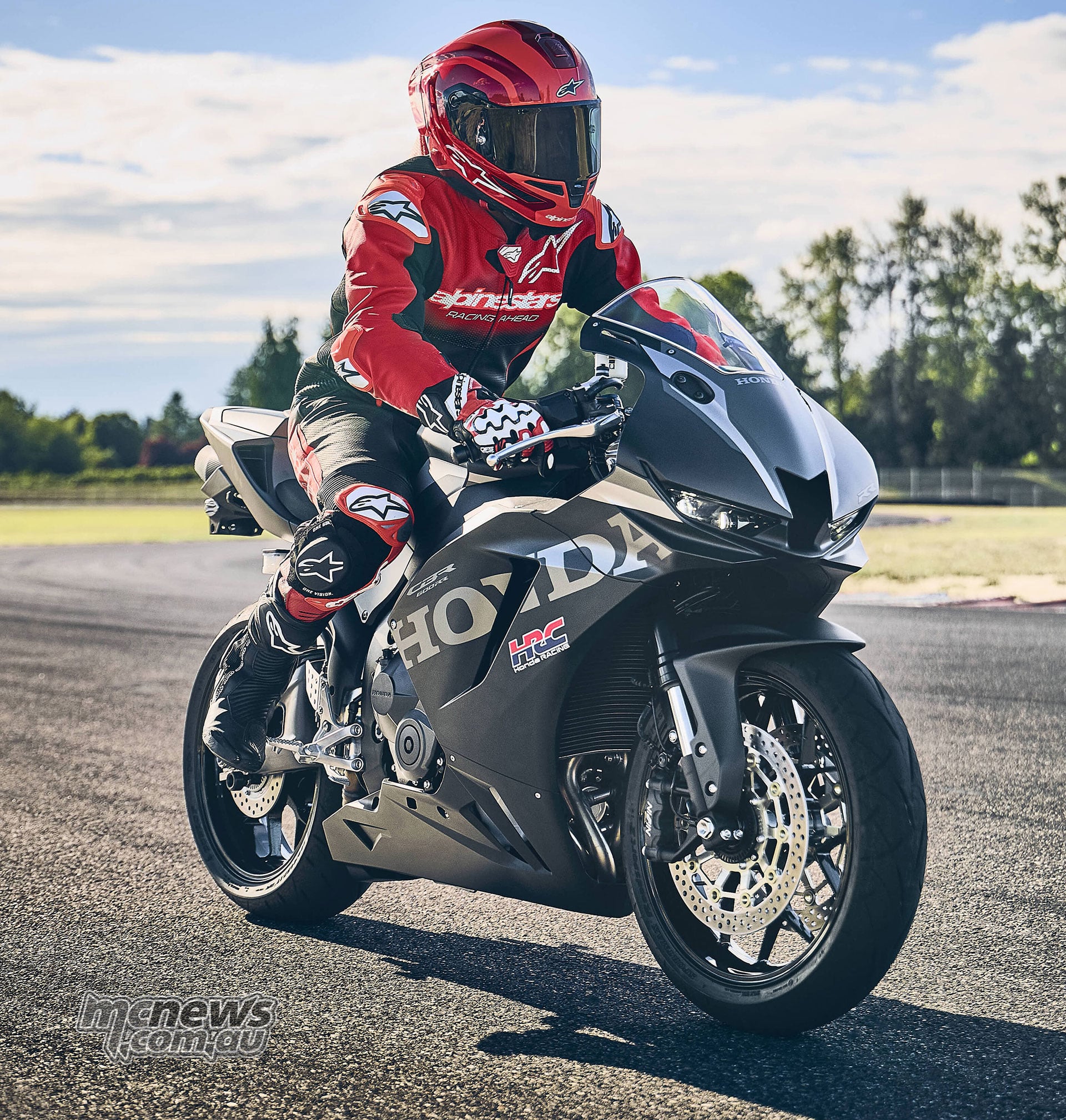 Rider in red and black leathers seated on a black 2027 Honda CBR600RR outdoors
