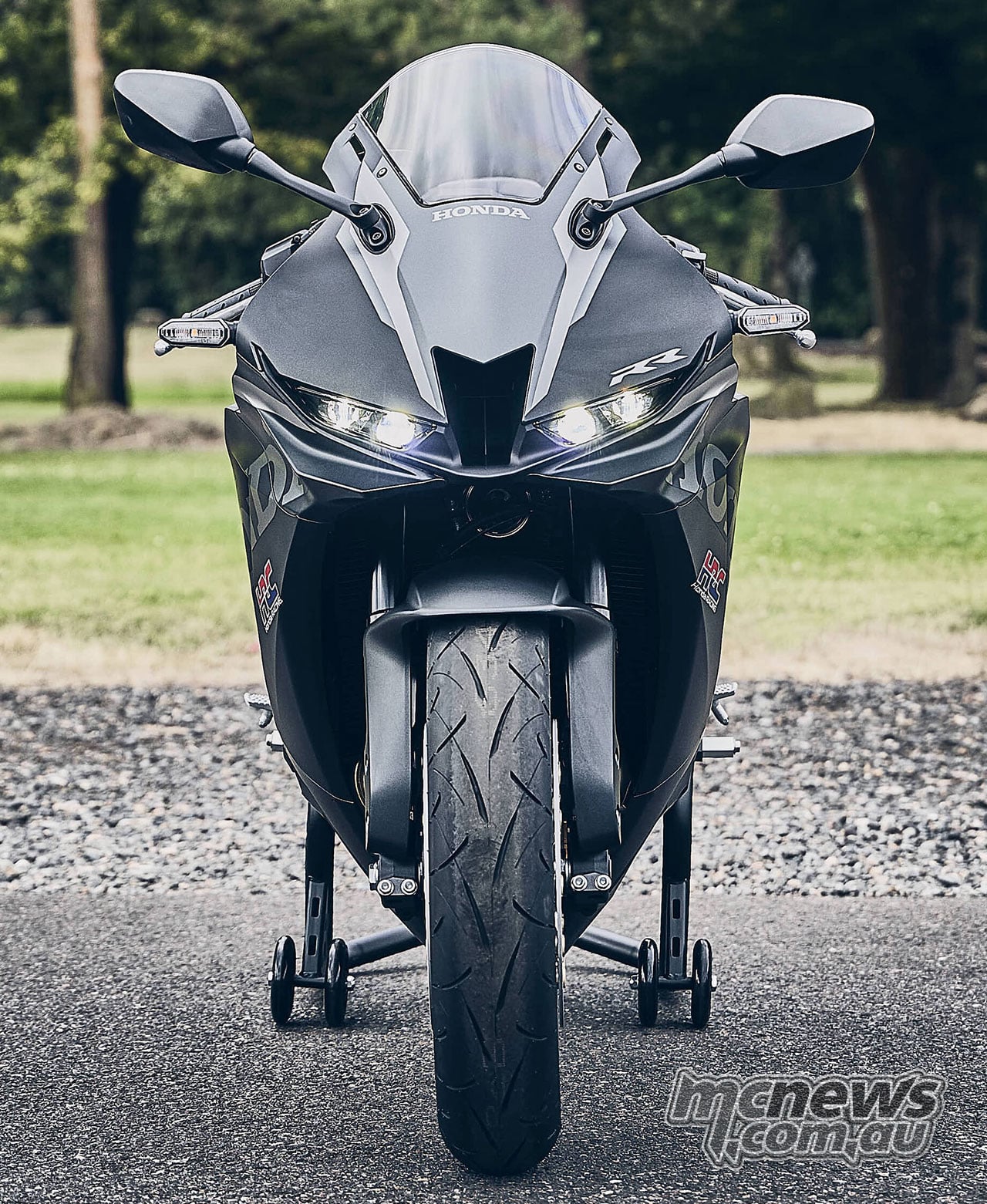 Front view of the black 2027 Honda CBR600RR on a paddock stand with its LED headlights illuminated