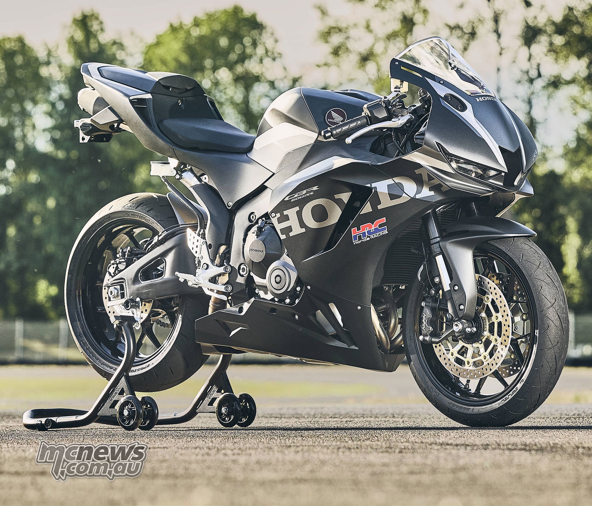 Front right three-quarter view of the black 2027 Honda CBR600RR on a rear paddock stand outdoors