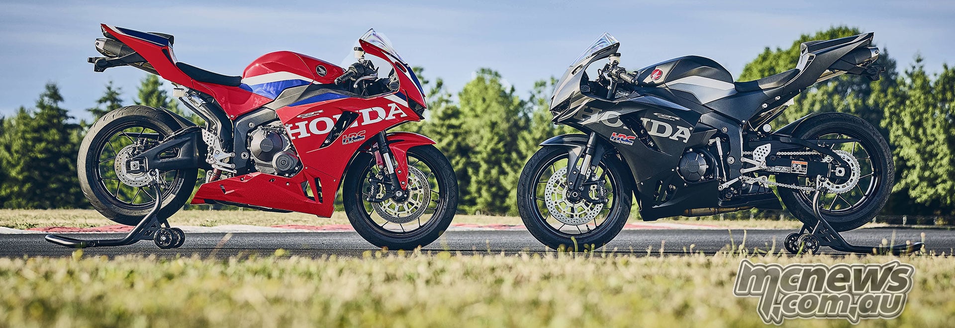 Red and black 2027 Honda CBR600RR motorcycles facing each other on rear paddock stands outdoors