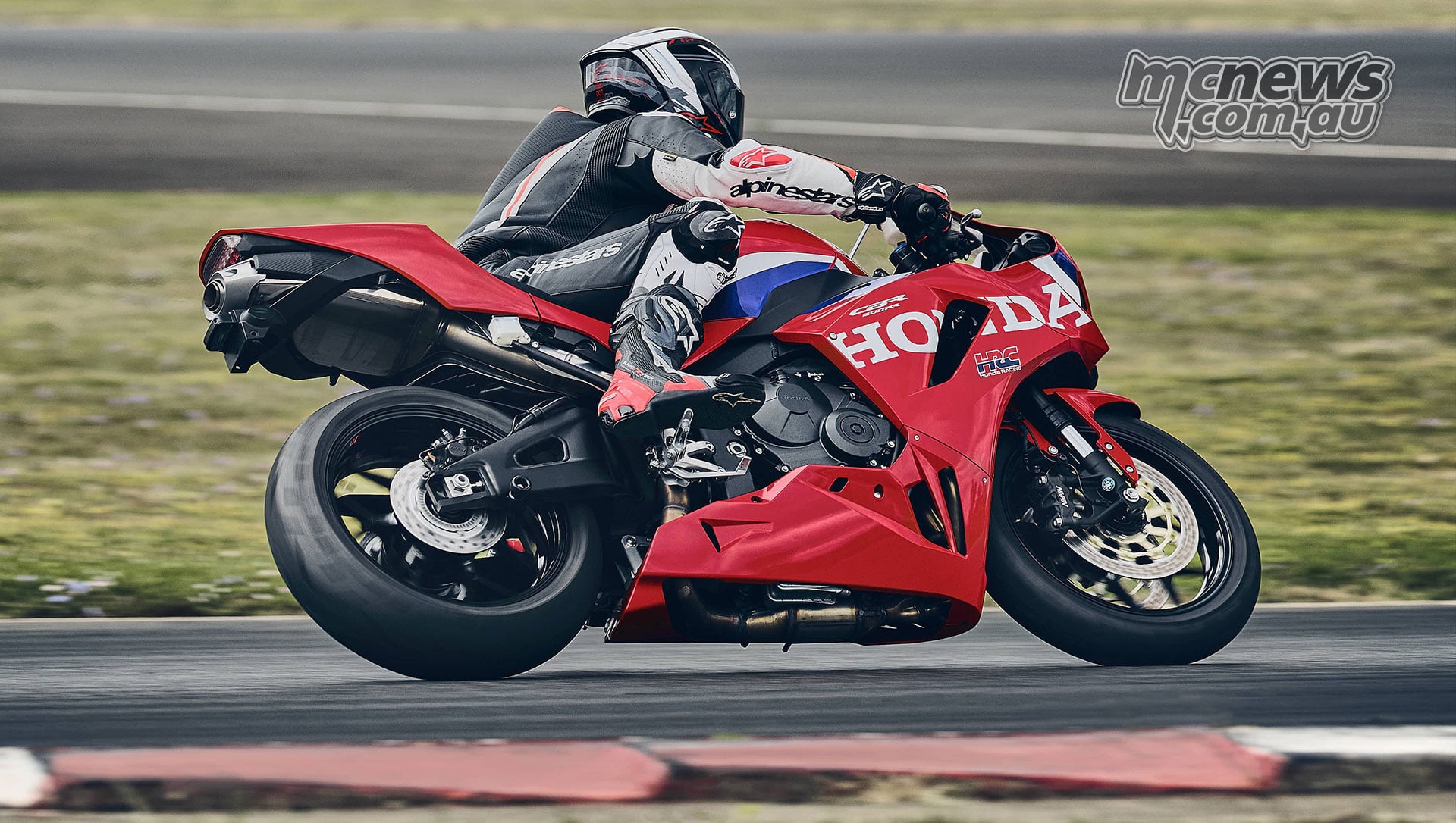 Rear right action view of a rider cornering on the red 2027 Honda CBR600RR at a circuit