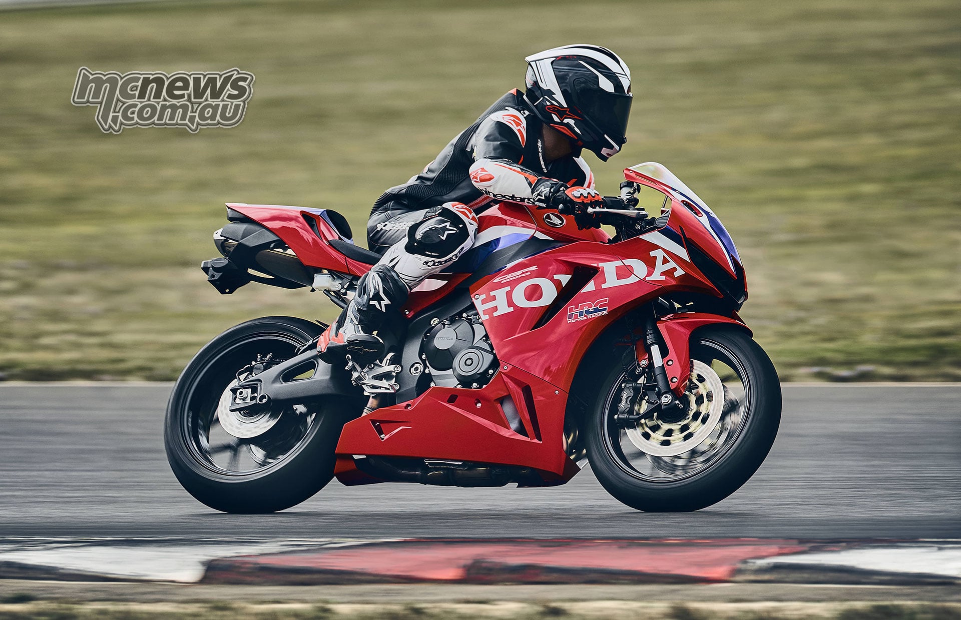 Right-side action view of a rider leaning the red 2027 Honda CBR600RR through a circuit corner
