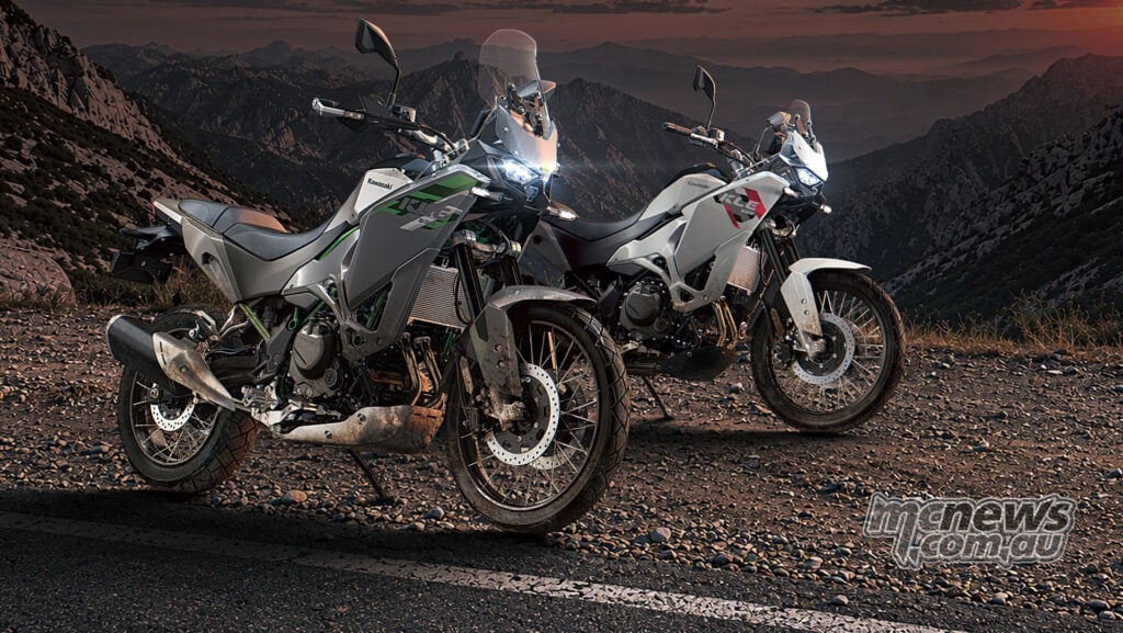 Two Kawasaki KLE650 adventure motorcycles parked on gravel with mountains behind them.