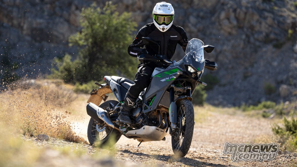 Rider turning a Kawasaki KLE650 SE across a loose dirt surface with dust behind the rear wheel.