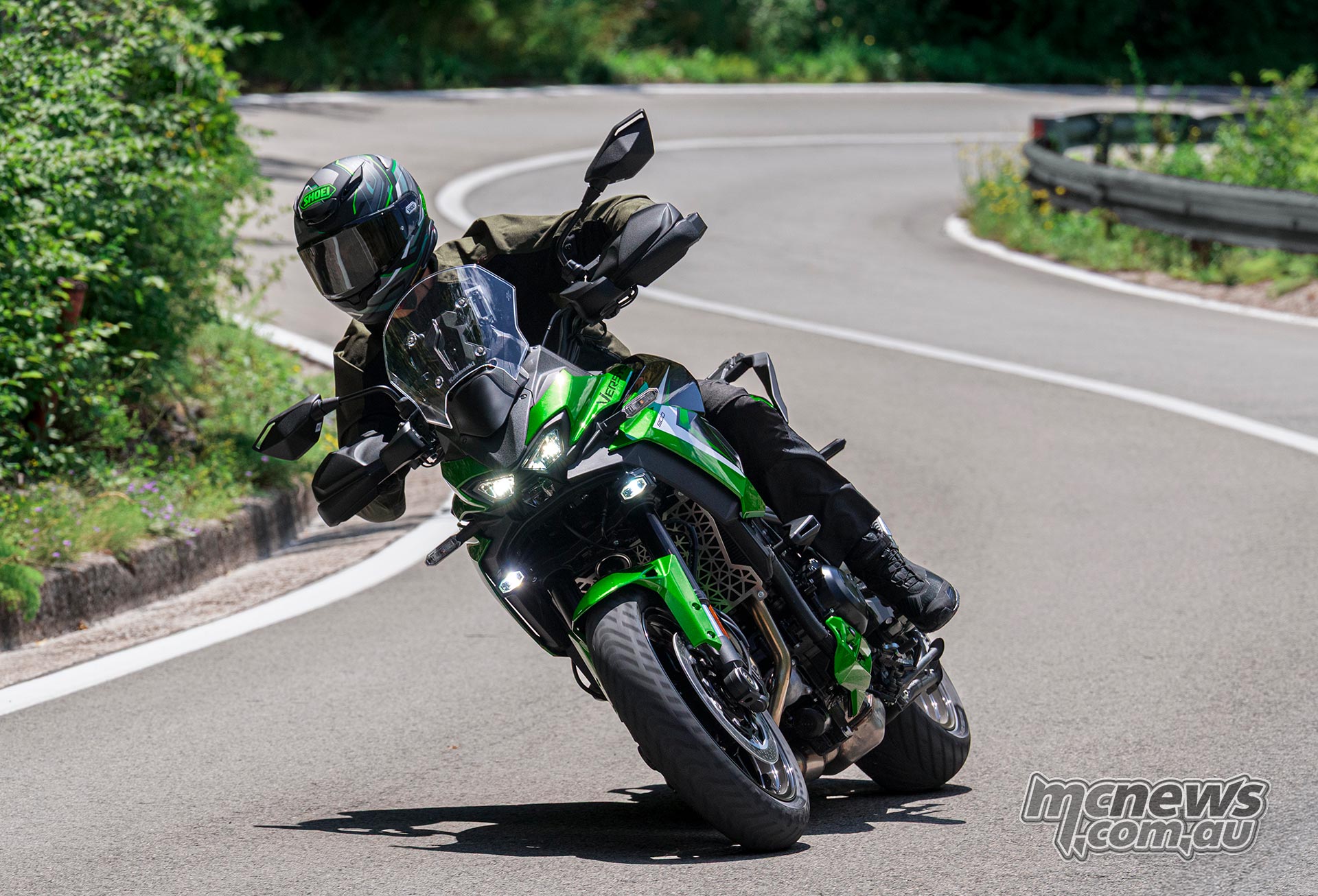 Rider leaning a green 2027 Kawasaki Versys 900 SE through a winding road bend