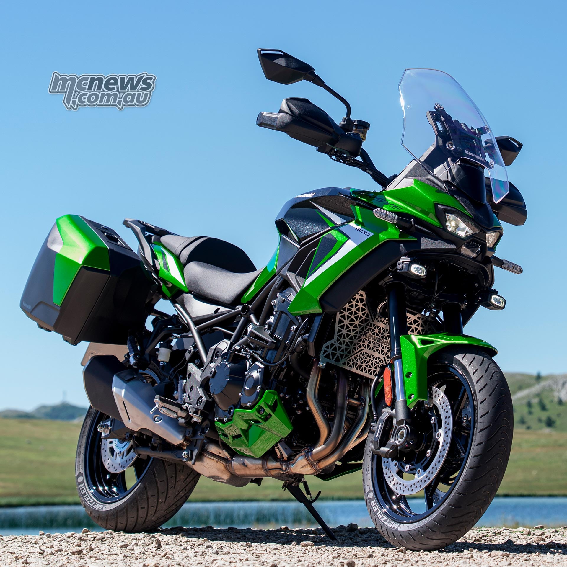 Low front three-quarter view of a green Kawasaki Versys 900 SE with panniers parked on gravel