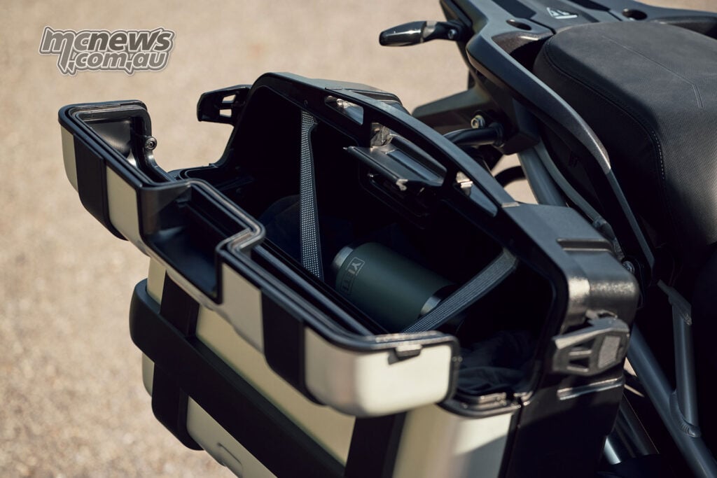 An open aluminium accessory pannier mounted beside the seat of a 2027 Triumph Tiger 1200 GT Pro.