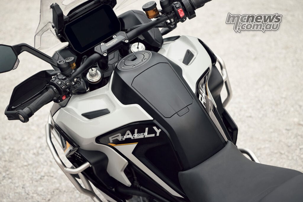 View over the seat and fuel tank of a 2027 Triumph Tiger 1200 Rally Explorer towards its handlebars and rectangular TFT display.
