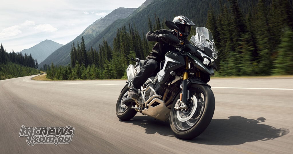 A rider corners on a green 2027 Triumph Tiger 1200 Rally Pro on a mountain road.