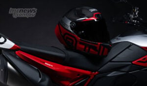 Matching Ducati helmet in red, silver and black sitting on the Hypermotard V2 SP 100 seat beside the anniversary model’s rear bodywork.