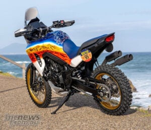 Rear three-quarter view of Honda XL750 Transalp Dakar Tribute custom with twin exhausts and gold wheels