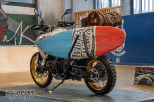 Rear view of Honda XL750 Transalp Ocean Nomad custom carrying a surfboard and canvas luggage