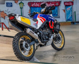 Indoor rear three-quarter view of Honda XL750 Transalp Saharja custom with gold wheels and rally bodywork