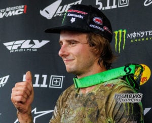 Levi Kitchen gives a thumbs-up in muddy racewear, wearing a Kawasaki cap with green goggles around his neck.