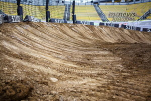 Freshly prepared banked corner on the Columbus SMX track, with grooming marks and empty yellow grandstands.