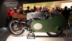 The 500cc Otto Cilindri still draws a crowd, nearly seven decades after Moto Guzzi left Grand Prix racing. Green-faired Moto Guzzi 500cc V8 with a silver tank and brown seat, surrounded by visitors in the museum.