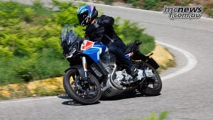 Rennie Scaysbrook takes the Stelvio onto the roads around Lake Como. Rennie Scaysbrook leans a blue, white and red Moto Guzzi Stelvio through a bend on a tree-lined road.