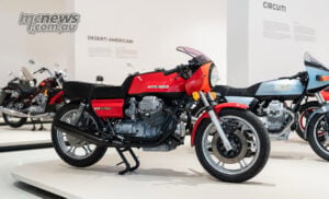 A Le Mans 850 in the new museum. Le Mans models were among the many generations of Guzzi represented in the anniversary parade. Red Moto Guzzi Le Mans 850 with an exposed V-twin engine and small front fairing on a white museum display.