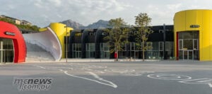 A new gathering place at an old address: the redeveloped courtyard keeps Moto Guzzi’s next chapter firmly rooted in Mandello. Empty Moto Guzzi courtyard with an eagle graphic on the ground, a yellow café entrance and mountains behind.